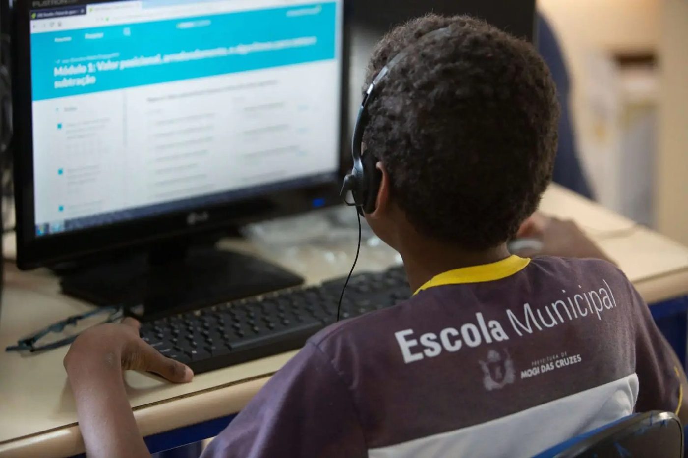 Aluno da rede municipal usando computador em laboratório de informática